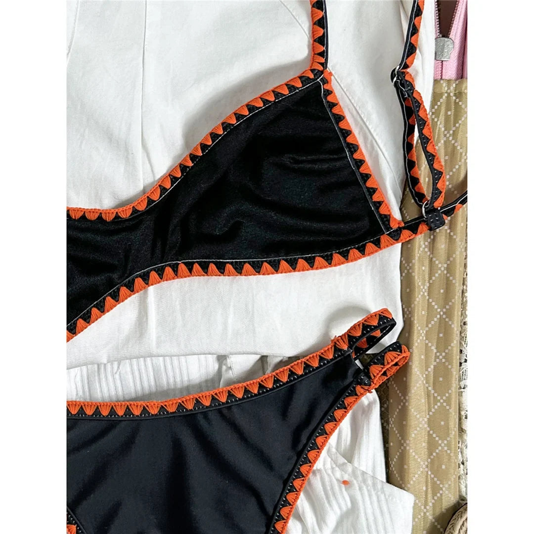 Bikini brésilien triangle imprimé fleuri noir et orange, gros plan sur le triangle du haut et ses fleurs orange