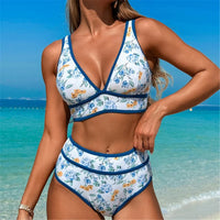 Bikini décolleté en V à fleurs bleues et jaunes porté de face sur la plage, bordure bleu marine et taille haute