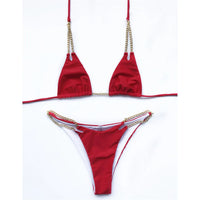 Bikini tour de cou à chaîne métallique rouge posé à plat sur fond blanc, chaînes dorées sur la culotte