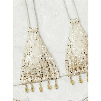 Gros plan sur le haut à sequins beige orné de petites coquilles dorées en franges qui pendent sous les triangles