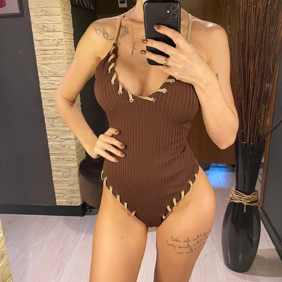 Maillot de bain une pièce côtelé marron foncé porté de face, main sur la hanche, bordures lacées beige au col v