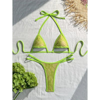 Bikini string micro vert fluo en dentelle, bordure verte et liens longs, posé à plat sur lin blanc avec hortensia