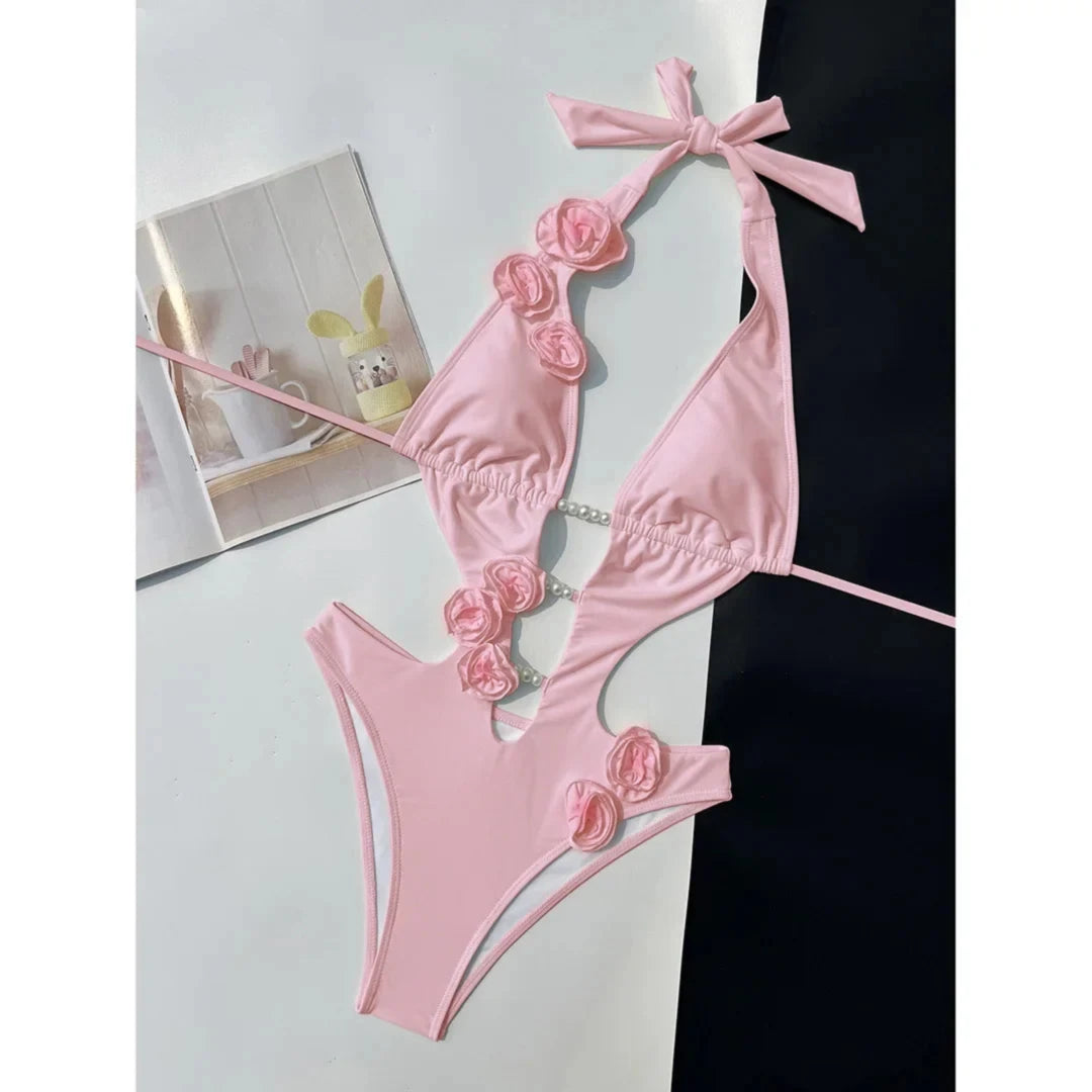Maillot de bain une pièce décolleté V fleurs 3D rose posé à plat, fleurs roses en relief sur les bonnets et les côtés découpés