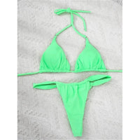 Bikini triangle froncé vert menthe posé à plat sur un tapis texturé blanc, bretelles fines étirées