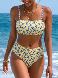 Bikini taille haute jaune clair à petites fleurs bleues et bretelles vichy, porté de face par une femme au bord de la mer