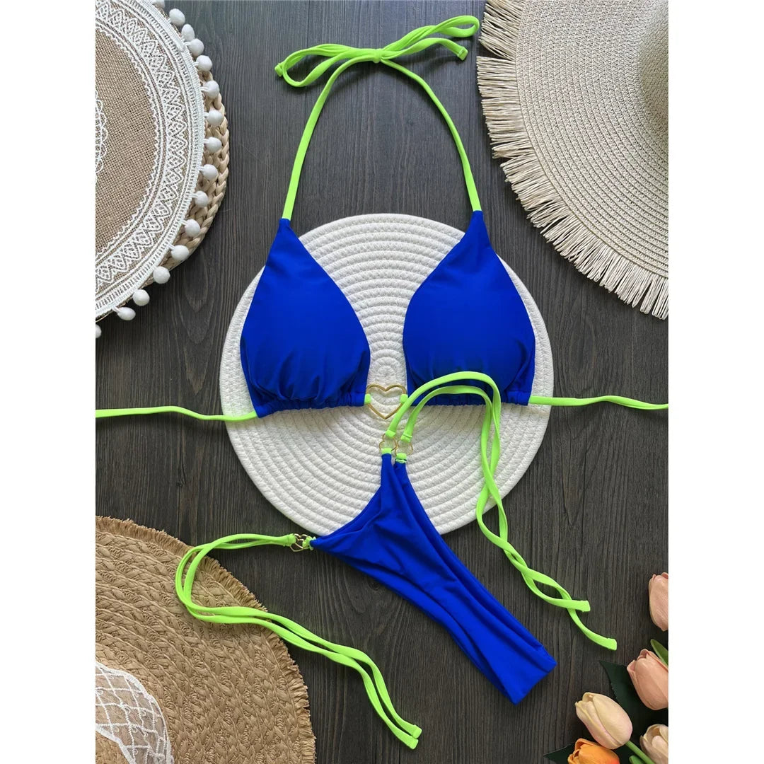 Bikini string tour de cou échancré à empiècements bleu roi posé à plat sur un tapis rond en corde et des sets en paille