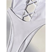 Gros plan sur les lanières croisées du décolleté en V d'un maillot une pièce blanc, coutures fines le long de la taille