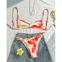 Bikini triangle échancré imprimé fleuri jaune crème posé sur un short en jean, bretelles fines et bas fleuri