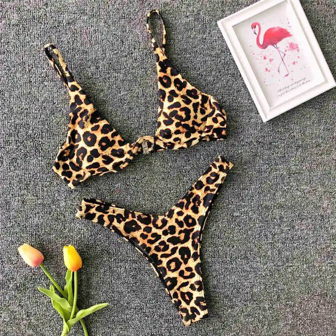 Bikini à armatures imprimé léopard posé à plat sur un tapis gris, haut en V profond et bas échancré