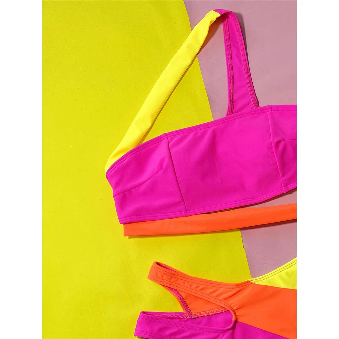 Gros plan sur le haut rose vif d'un bikini asymétrique, bretelle jaune et bande orange sous le bonnet