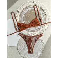 Bikini triangle échancré rouge brique à bretelles fines posé à plat sur des sets de table, bas à double bride