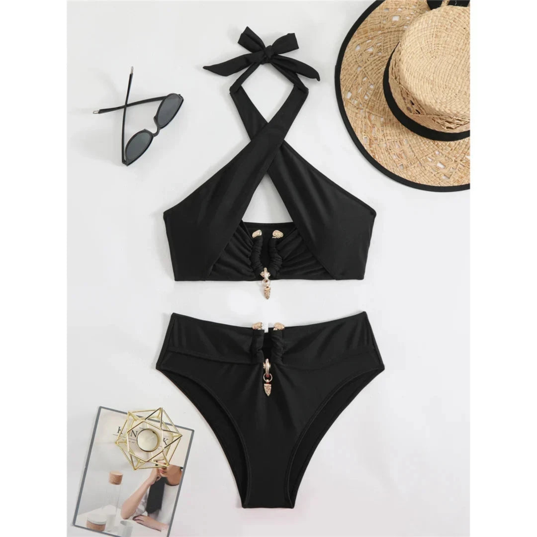 Bikini taille haute tour de cou à découpes noir posé à plat sur fond blanc, anneaux dorés et chapeau de paille