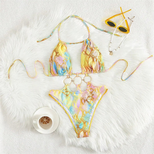 Maillot de bain tour de cou à anneaux imprimé jaune pastel posé à plat sur une fourrure blanche avec une tasse de café