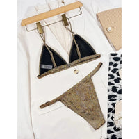 Bikini à paillettes doré posé à plat sur une veste blanche, triangle bordé de noir et bas échancré
