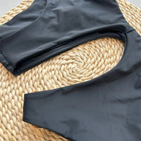 Gros plan sur les plis du tissu noir du maillot de bain une pièce asymétrique, bretelle et découpe sur l'osier
