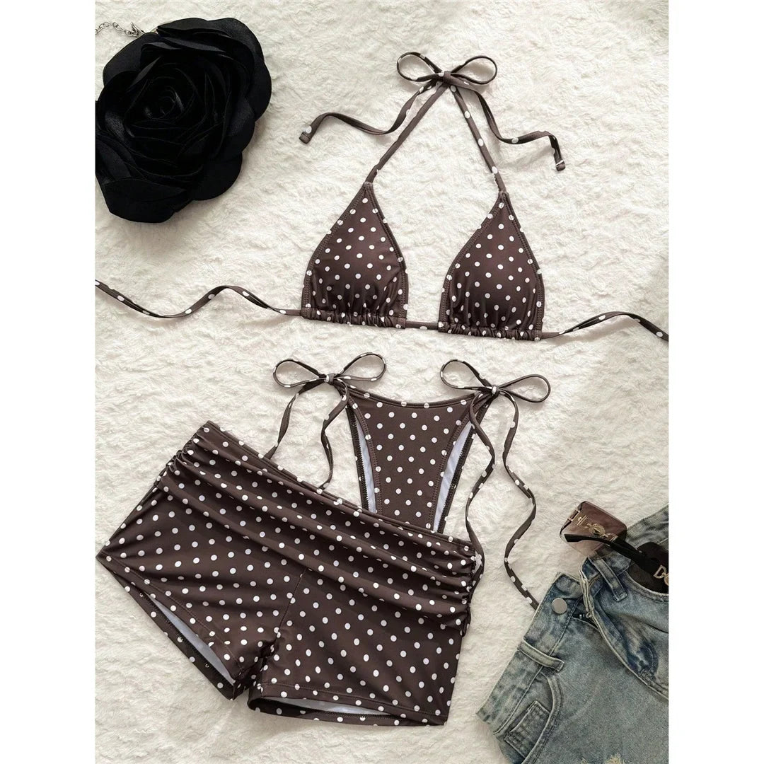 Maillot trois pièces à pois marron café posé à plat sur une surface blanche, avec short fronçé et lacets