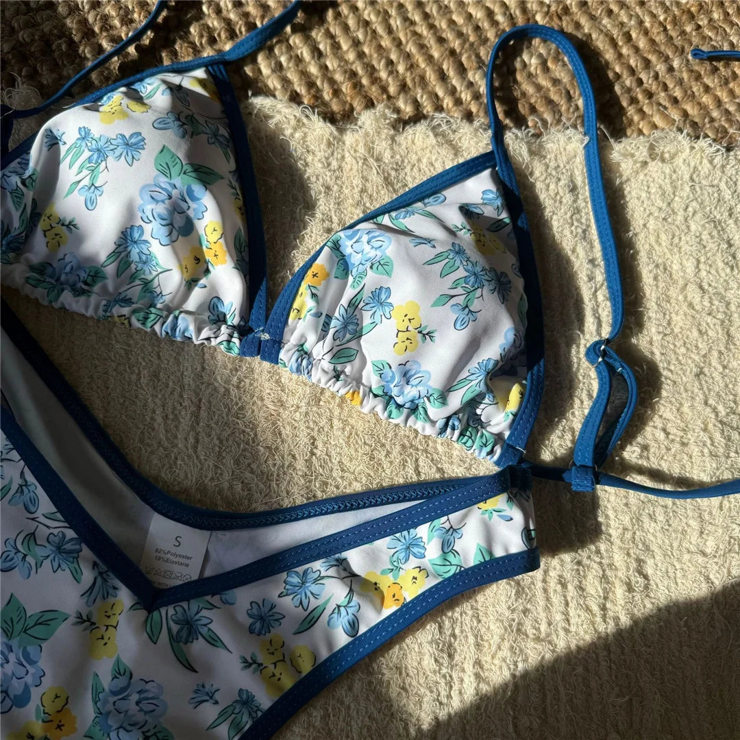 Gros plan sur le triangle imprimé fleuri bleu et jaune, liseré bleu et culotte bordée de bleu