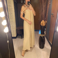 Longue robe beige en crépon portée de profil par une femme dans un intérieur à miroir, cordes sur les épaules