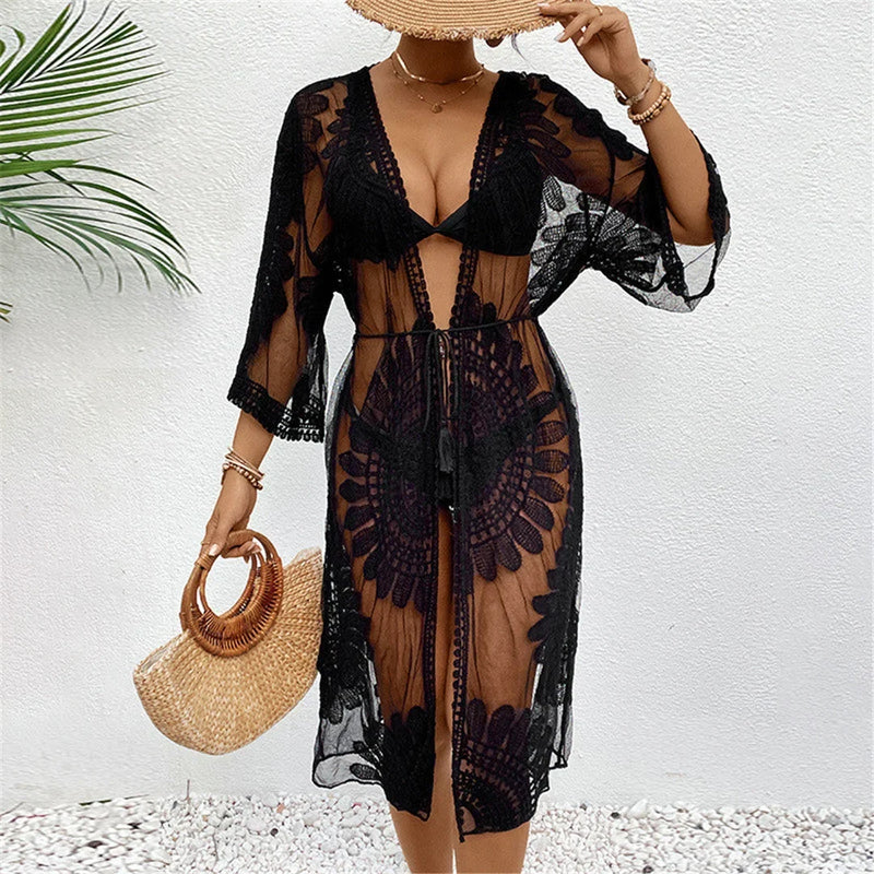 Cardigan de plage brodé en mousseline demi-manches noir porté de face, sac en osier à la main et motifs ajourés