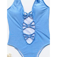 Gros plan sur les lacets croisés en V et les découpes du monokini bleu ciel uni, en plan rapproché