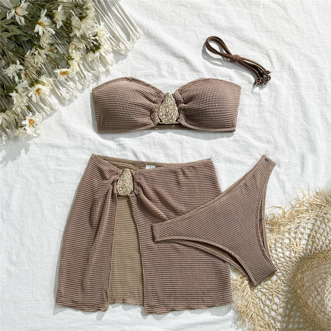 Ensemble trois pièces marron café posé à plat sur un tissu blanc, bandeau à ornement, jupe et bas brésilien