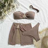 Ensemble trois pièces marron café posé à plat sur un tissu blanc, bandeau à ornement, jupe et bas brésilien