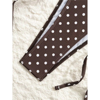 Gros plan sur le bord du short marron café à pois blancs, avec les lacets et la couture visible