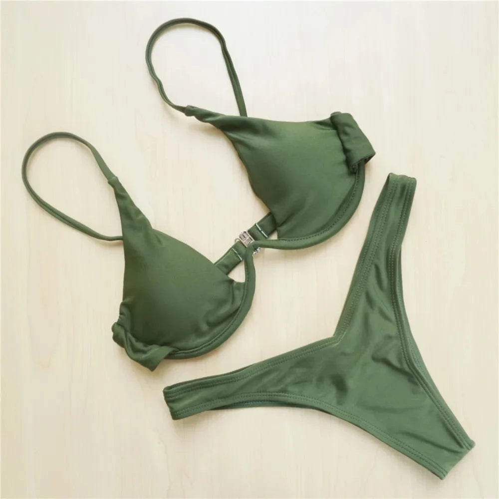 Bikini à armatures rembourré à haut en V profond vert posé à plat sur un fond beige, haut et bas bien séparés