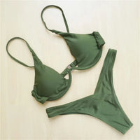 Bikini à armatures rembourré à haut en V profond vert posé à plat sur un fond beige, haut et bas bien séparés