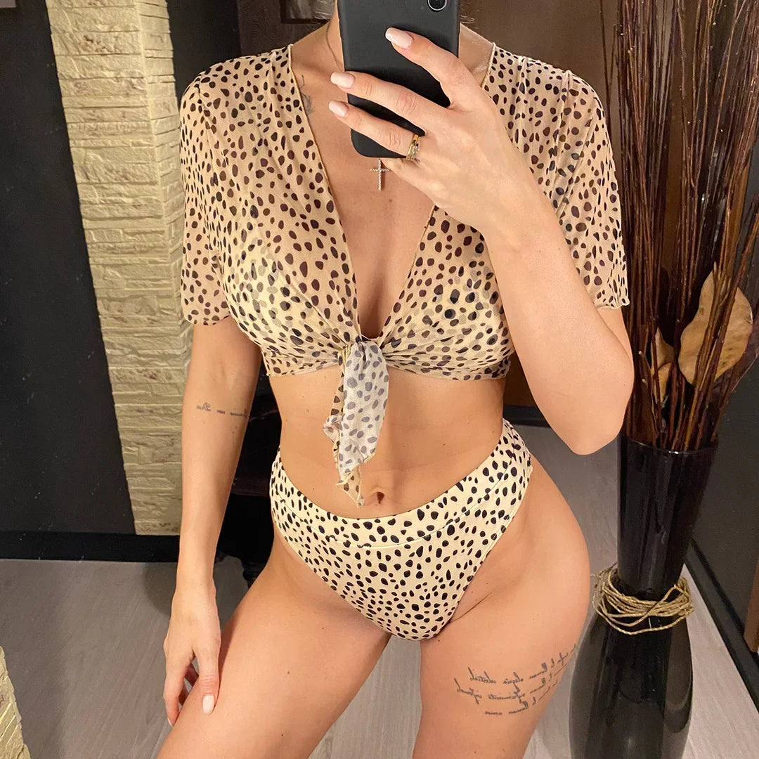 Maillot trois pièces taille haute imprimé léopard porté de face avec haut transparent à manches courtes noué devant