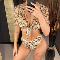 Maillot trois pièces taille haute imprimé léopard porté de face avec haut transparent à manches courtes noué devant