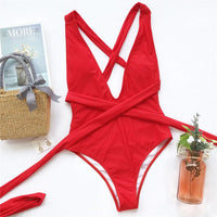 Maillot de bain une pièce triangle croisé rouge posé à plat sur fond clair, bretelles croisées et lien de taille déployé