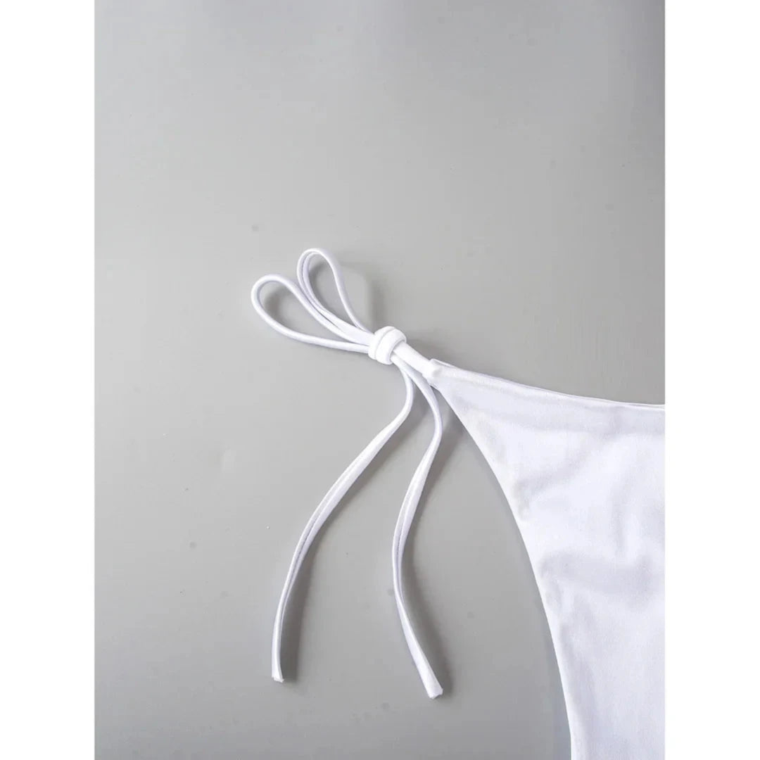 Gros plan sur les liens fins du bikini brésilien blanc noués sur le côté, sur fond gris