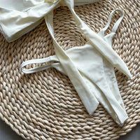 Bikini bandeau string échancré à étoile métallique beige vu de près, lanières fines du slip et bord du haut en gros plan