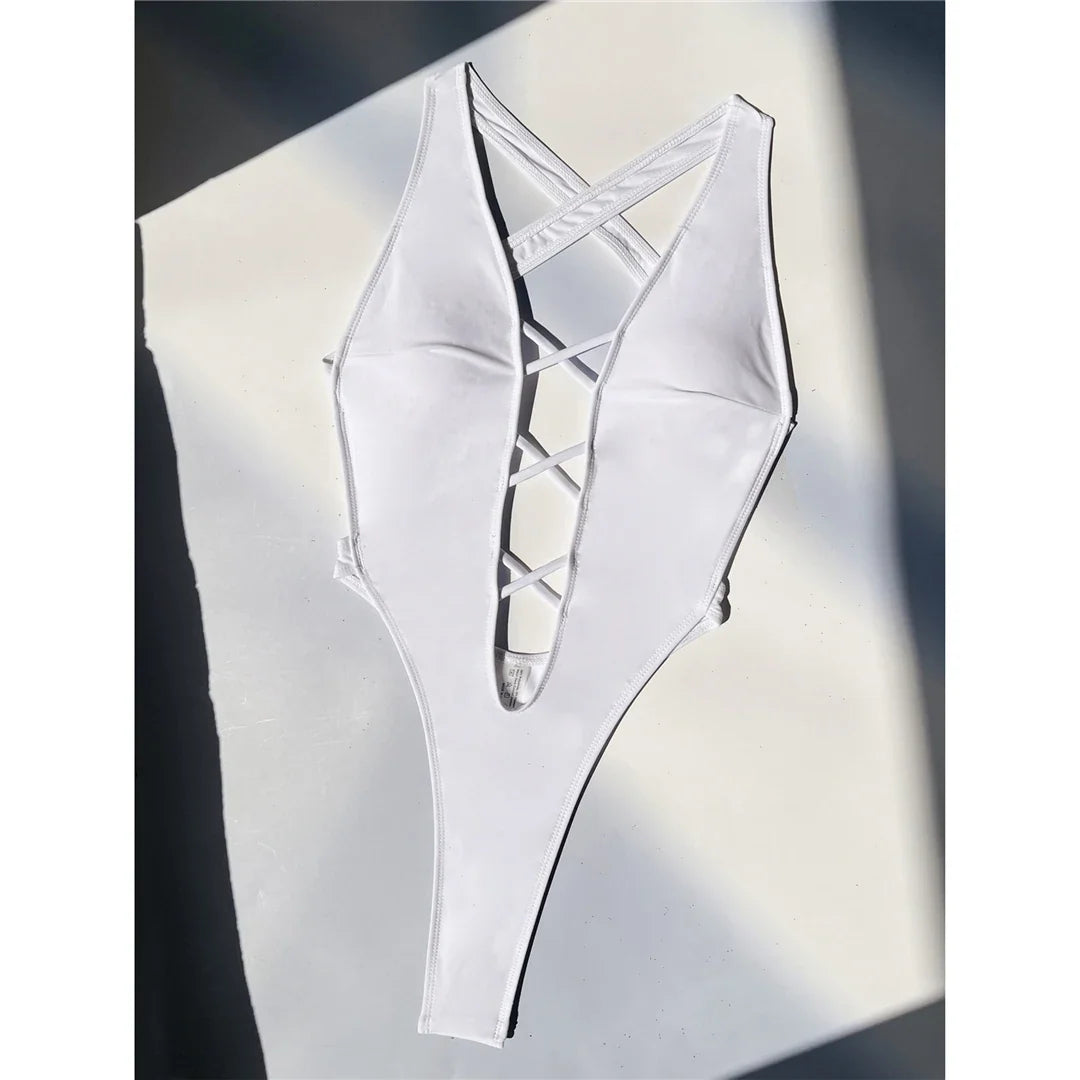 Maillot une pièce échancré blanc étalé à plat sur un fond clair ensoleillé, décolleté en V et lanières croisées au centre