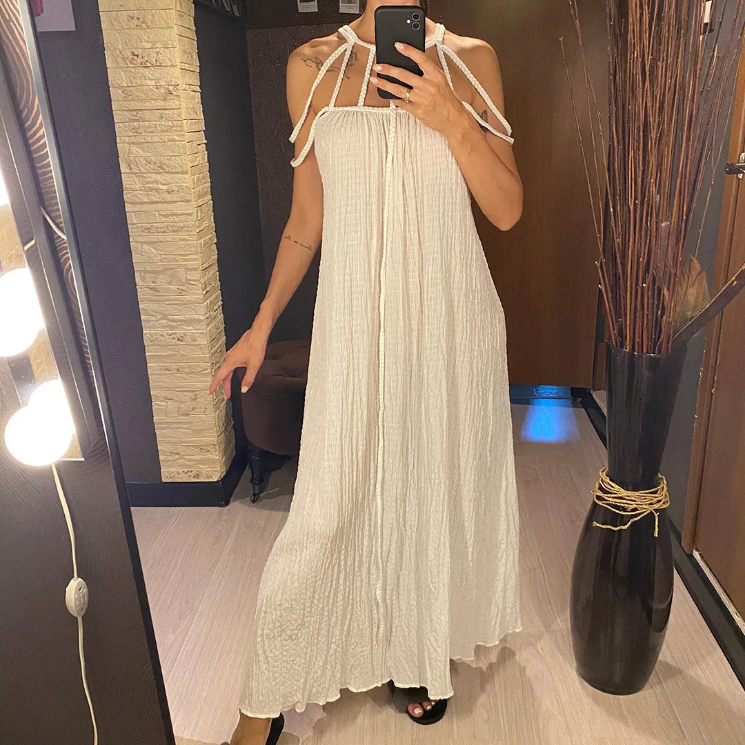 Longue robe blanche à bretelles nouées sur les épaules, ample et plissée, portée de face dans un intérieur à miroir