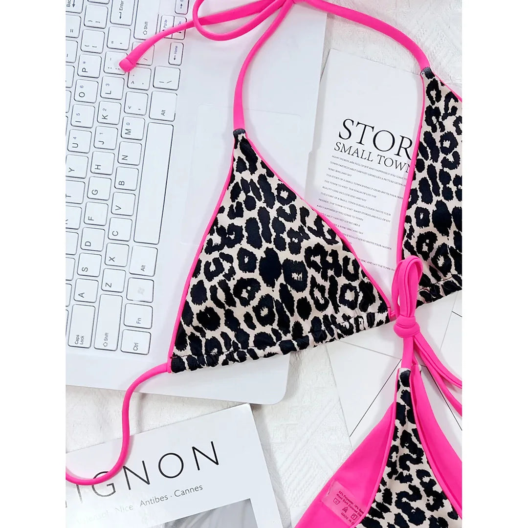 Gros plan sur le haut triangle imprimé léopard noir et beige, bordure rose fuchsia et lacet de cou sur un clavier