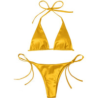 Bikini brésilien satiné jaune posé à plat sur fond blanc, haut triangle à bretelles de cou et bas à lacets latéraux