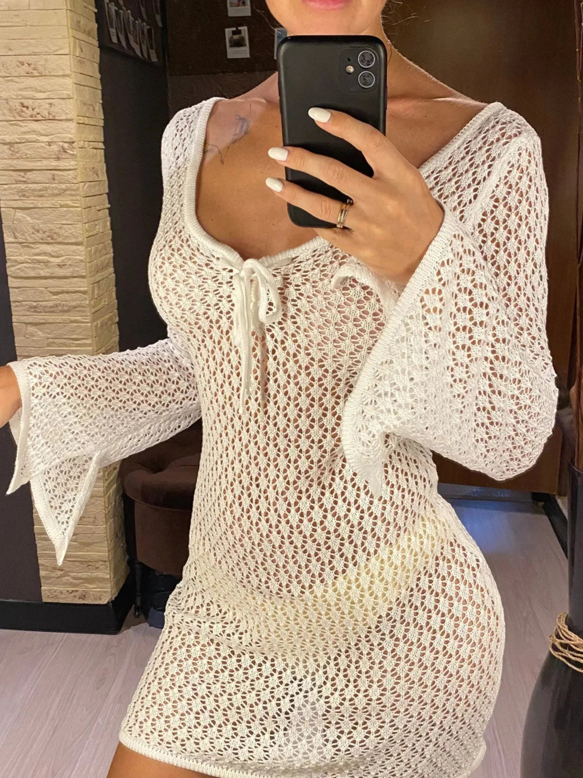 Tunique de plage crochet ajourée blanc col en V portée de face par une femme, lien noué au décolleté dans une pièce lumineuse