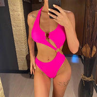 Monokini une pièce asymétrique tour de cou rose fuchsia porté de face devant un miroir, anneau doré et découpe latérale