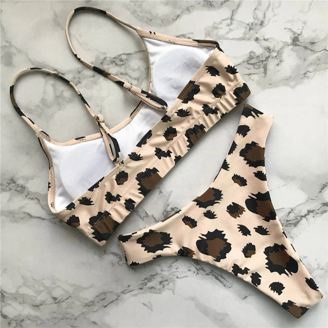 Bikini bralette à imprimé léopard beige aux taches brunes, posé à plat sur un fond marbré gris