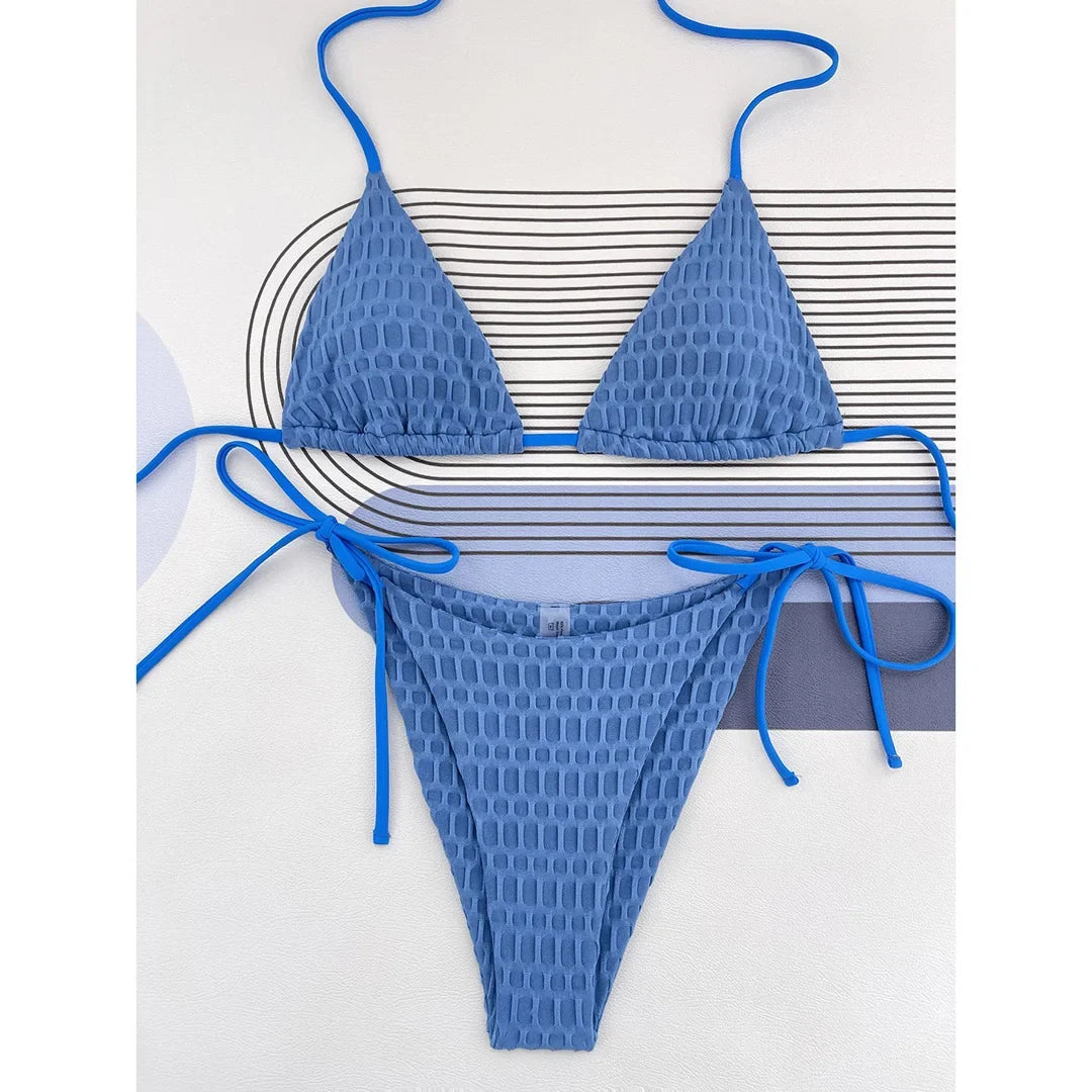 Bikini brésilien tour de cou bleu texturé à plat sur un fond blanc rayé, bretelles fines et bas à liens noués