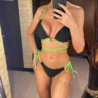 Bikini col halter croisé à effet froissé noir porté de face, bonnets texturés et lacets verts sur les hanches