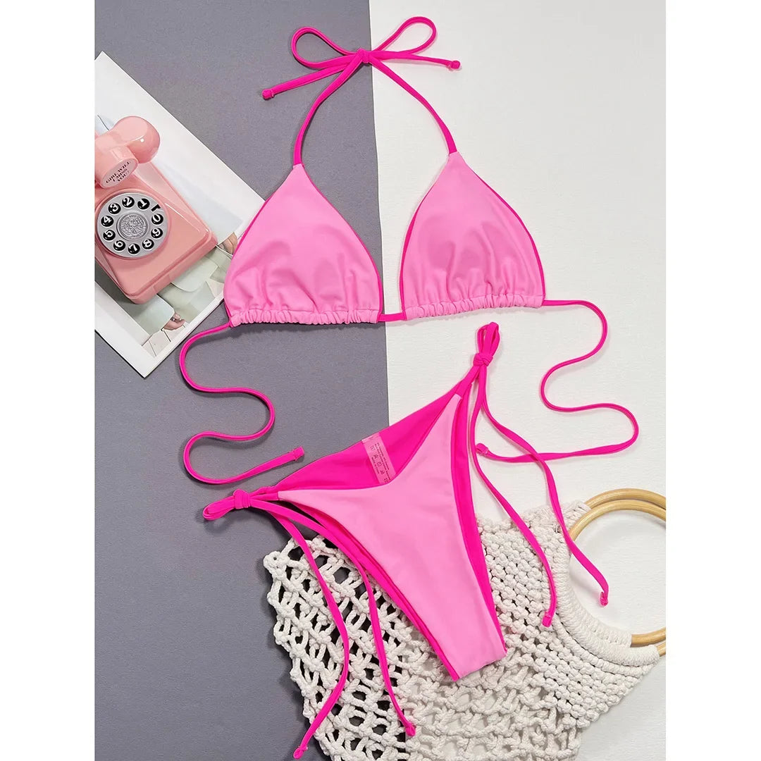 Bikini brésilien col halter taille basse rose posé à plat avec téléphone rétro et sac en filet, liens longs de chaque côté