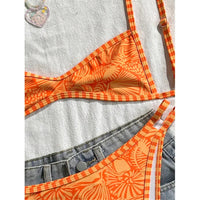 Gros plan sur le triangle orange imprimé du bikini brésilien, posé sur une serviette blanche au-dessus d'un short en jean
