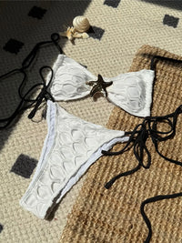 Bikini échancré à lanières et étoile métal blanc posé à plat, étoile dorée au centre et bas à lanières latérales