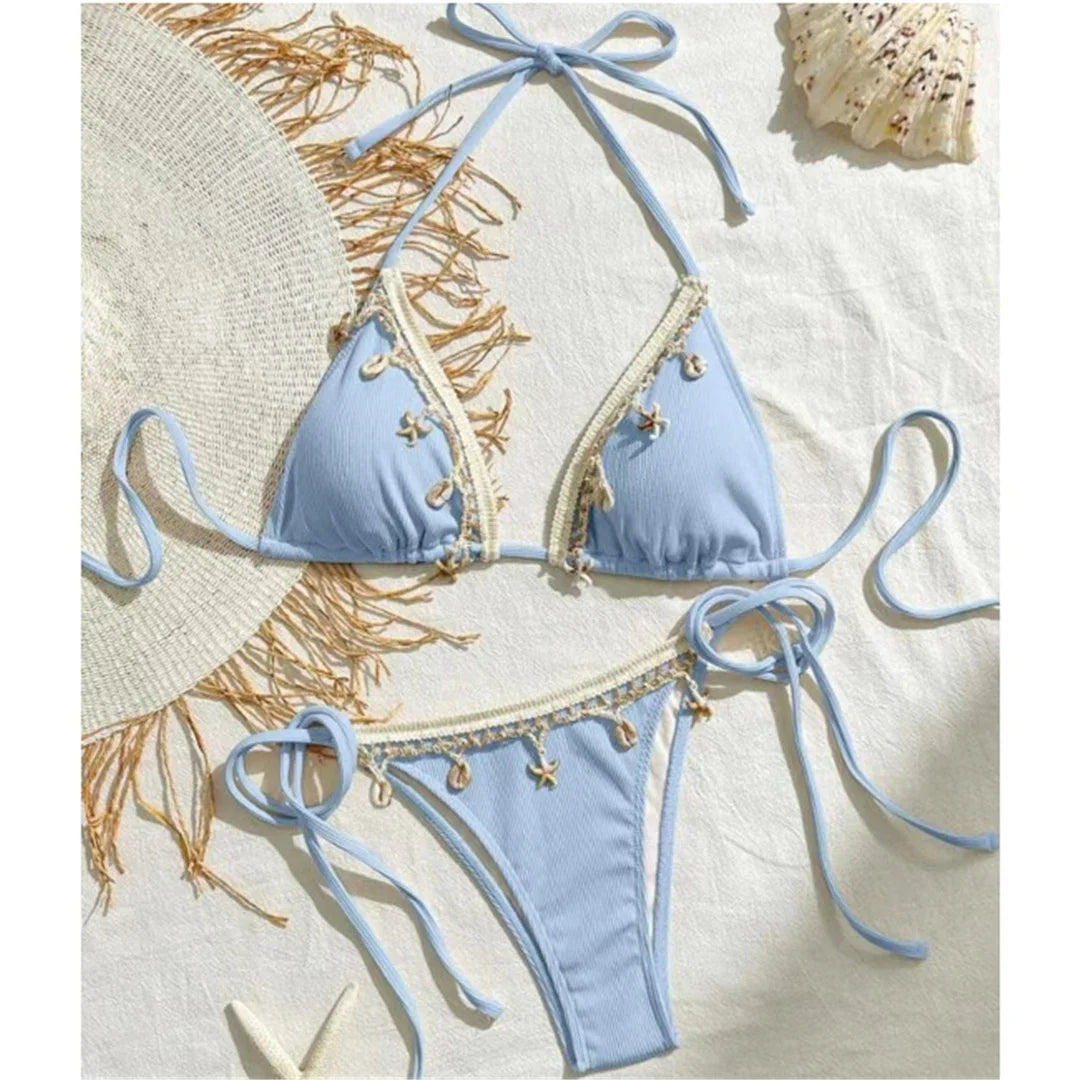 Bikini brésilien tour de cou patchwork à lanières bleu ciel posé à plat avec chapeau de paille et coquillages
