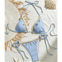 Bikini brésilien tour de cou patchwork à lanières bleu ciel posé à plat avec chapeau de paille et coquillages