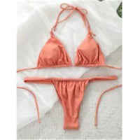 Bikini triangle froncé rose nude posé à plat sur un tissu blanc, bretelles fines étirées au premier plan