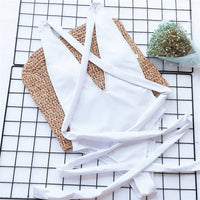 Maillot de bain une pièce triangle croisé blanc posé à plat sur une grille, lanières longues déployées